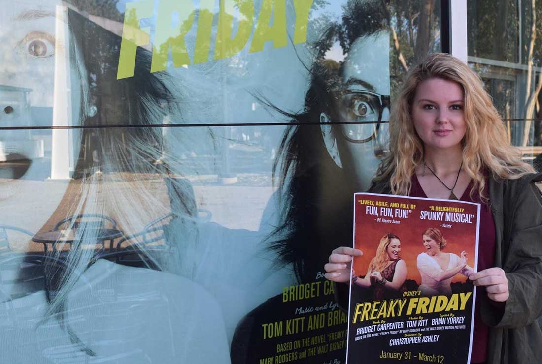 Abby Sherlock posing with "Freaky Friday" play poster in front of large poster ad
